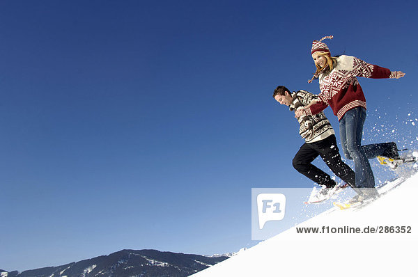 Young couple in snow  running downhill