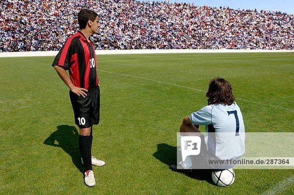 Two soccer players waiting on pitch