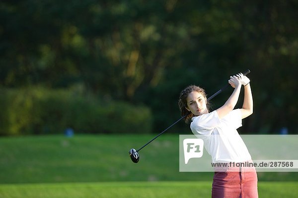 Eine junge Frau macht einen Strich mit einem Golf club