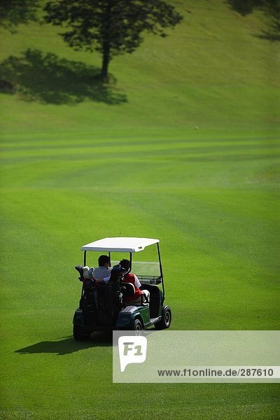 Rückansicht des zwei Golfer sitzen in einem Golf-cart