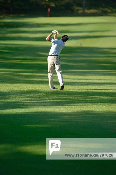 Male golfer hitting towards the green