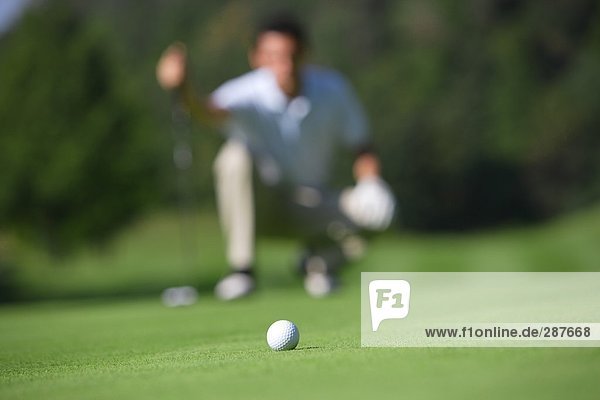 Mann betrachten ein Golfball auf einem Putting Green