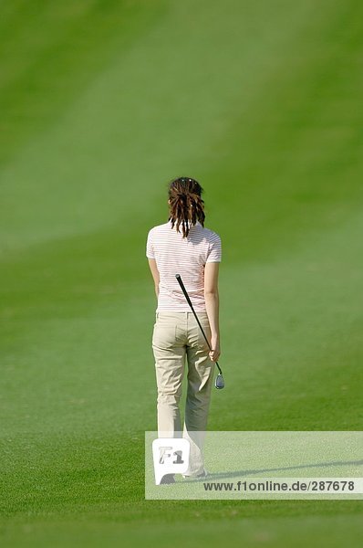 Junge weibliche Golfer zu Fuß nach unten ein Fairway