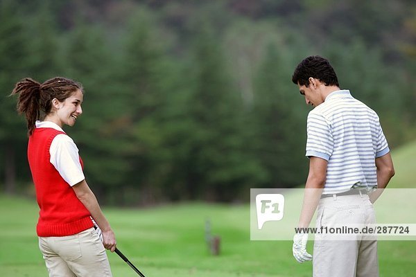 Side view of a couple chatting on the golf course