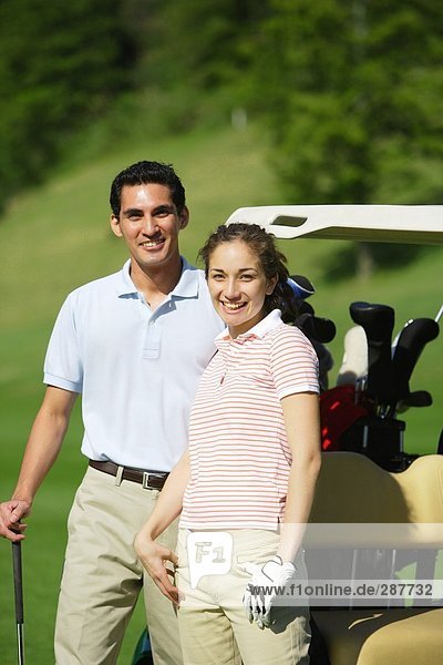 Couple standing near a golf cart