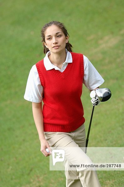 Weibliche Golfer zu Fuß zu den Tee Boden hält einen Golfschläger und einem ball