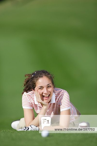 Frau Lächeln in die Kamera während des Ausruhens auf dem Golfplatz