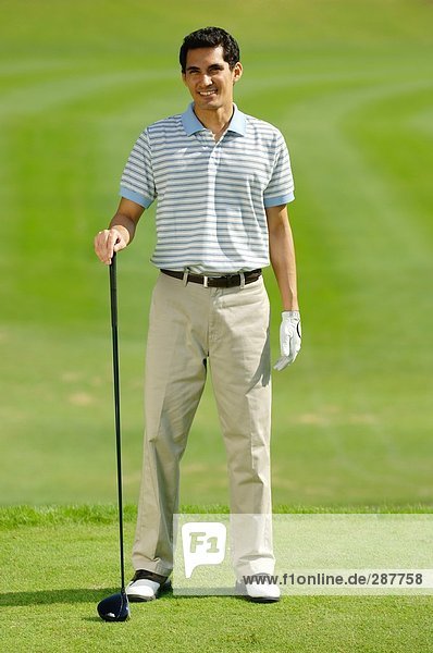 Mann an die Kamera hält einen Golfschläger posieren