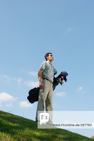 Low angle view of a man carrying a golf bag