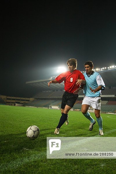 Zwei Fußball-Spieler jagen einen Ball