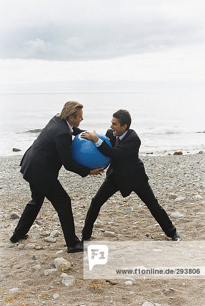 Two men fighting on a beach.