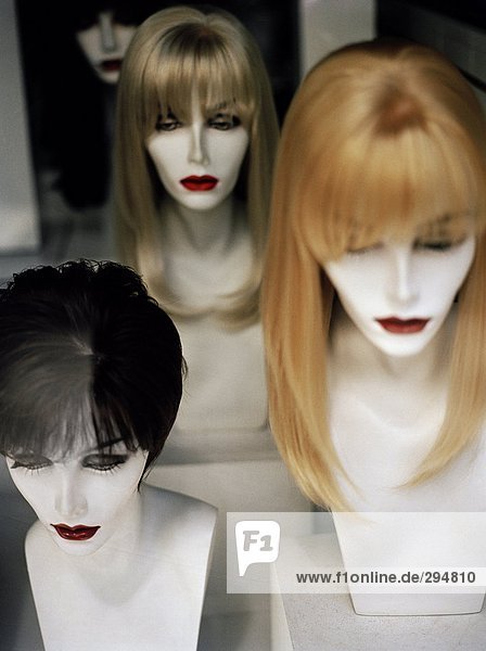 Perücken auf Mannequins in einem Shop-Fenster.