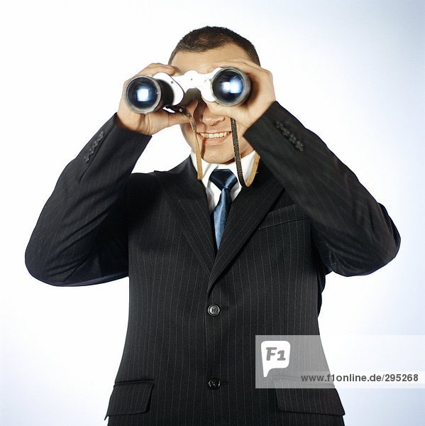 A businessman looking through a pair of binoculars.