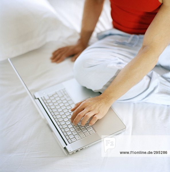 A person working on a laptop in bed.
