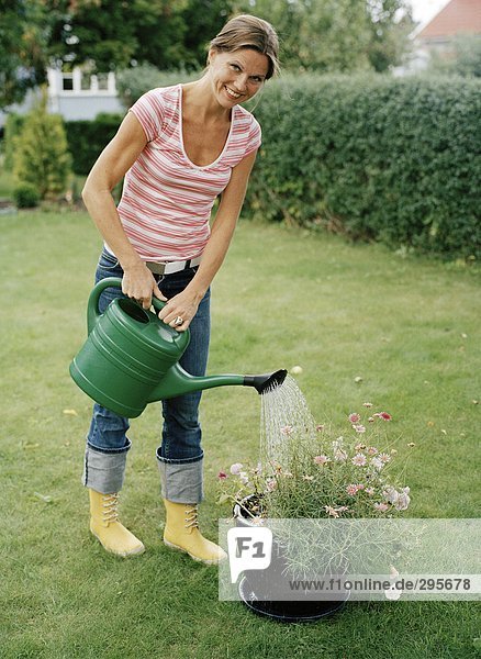 Portrait einer Frau Bewässerung von Pflanzen in einem Garten.