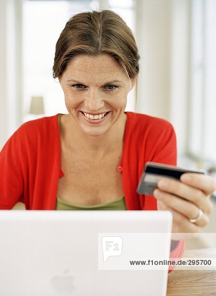 Eine Frau hält eine Kreditkarte arbeiten auf einem Laptop.