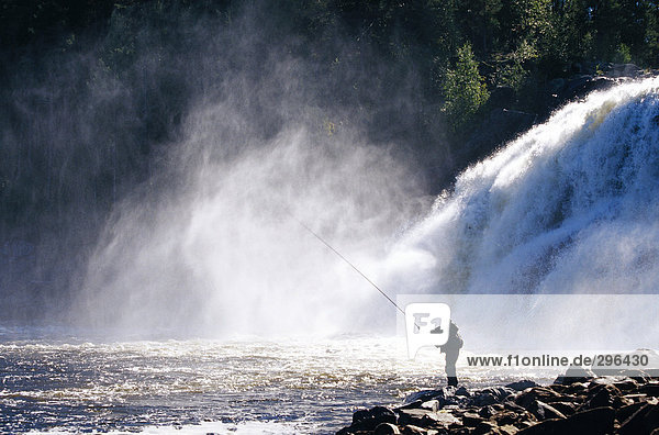 Ein Mann von einem Wasserfall Angeln.