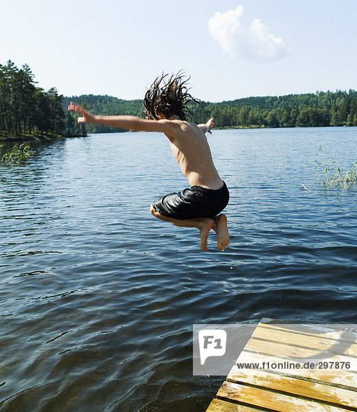 A boy jumping into a lake.