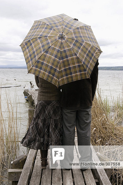 Paar am Steg mit Schirm  Rückansicht