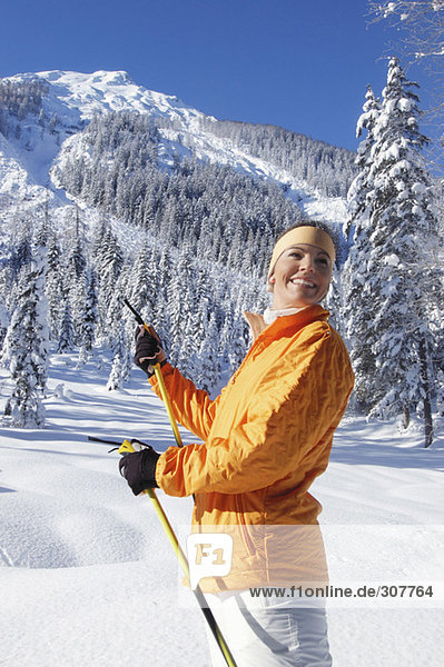 Junge Frau im Schnee mit Skistöcken