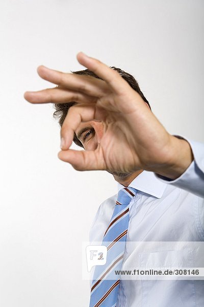 Young businessman gesturing ok sign (focus on background)