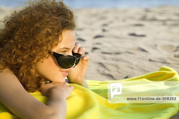 Junge Frau mit Sonnenbrille  Entspannung am Strand  Seitenansicht