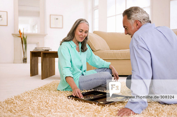 Reife Paare spielen Backgammon im Wohnzimmer
