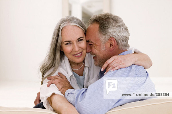 Mature couple embracing on sofa  smiling