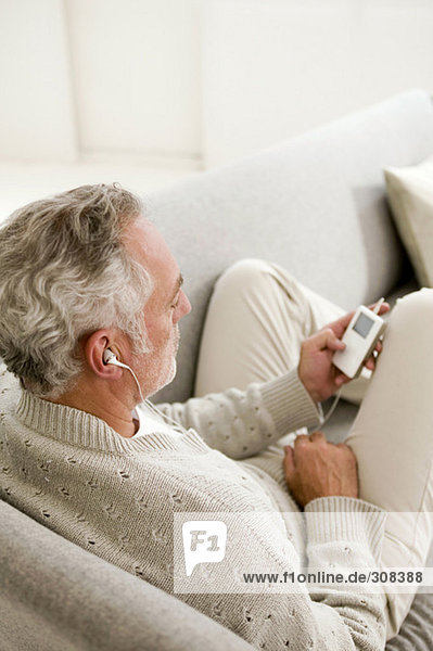 Mature man listening to MP3 player  close-up  elevated view