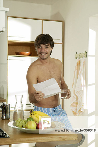 Junger Mann in der Küche  Brief haltend  lächelnd