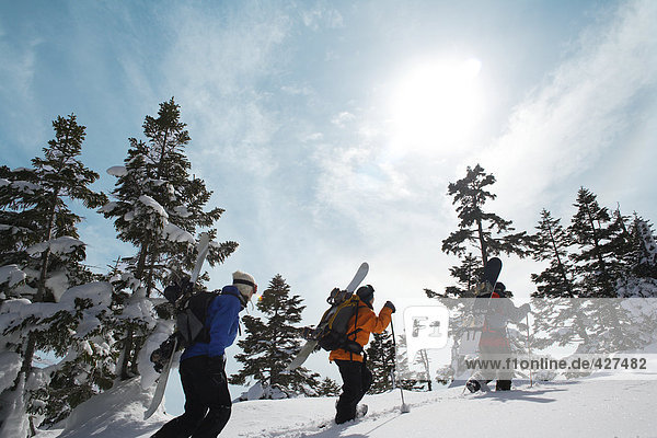 Drei Snowboarder zu Fuß durch Schnee