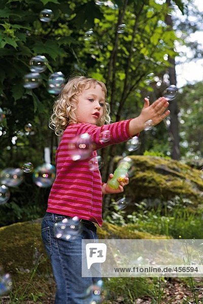 A girl blowing soap bubbles.