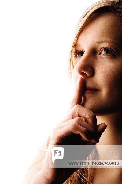 Portrait einer jungen Frau mit ihrem Finger auf ihre Lippen