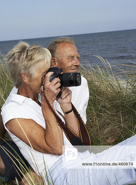 Middle-aged couple photographing at the beach.
