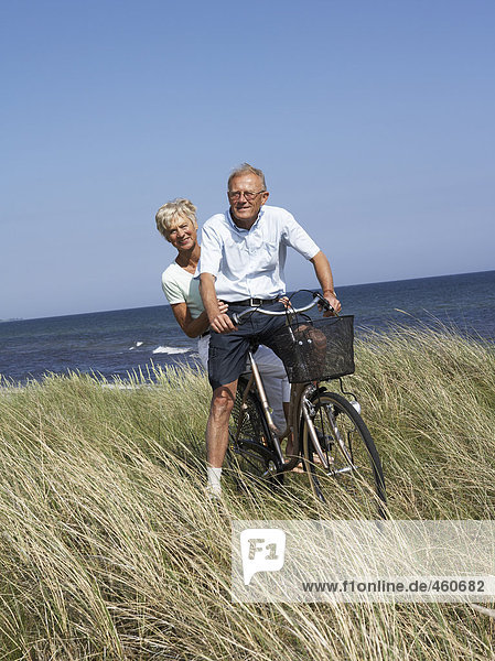 Middle-aged couple on bicycle by the sea.