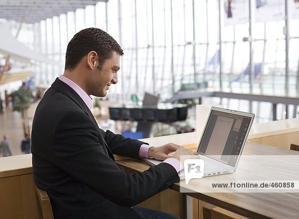 Ein Mann auf einem Flughafen auf einem Laptop arbeiten.