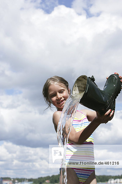 A girl pouring water from a boot.