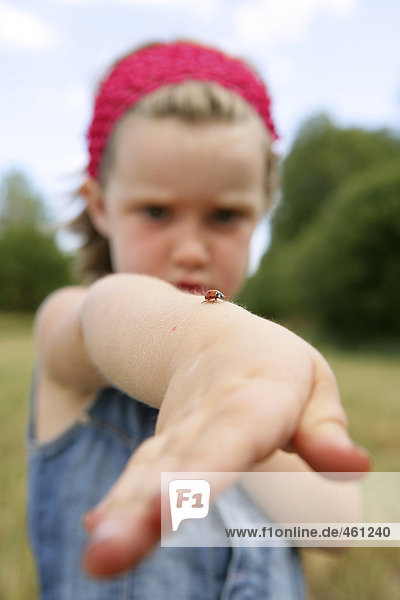 A girl with a ladybird on her hand.