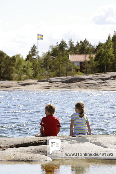 Two children sitting on a cliff in the archipelago.