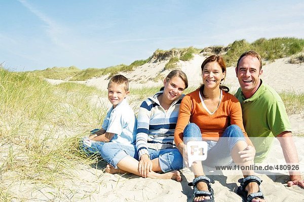 Portrait of family sitting on beach and smiling