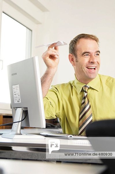 Businessman flying paper plane in office