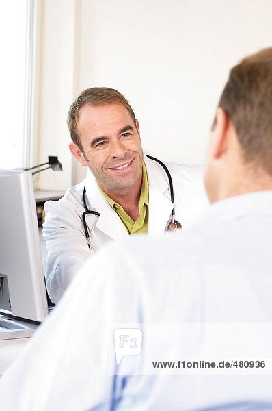 Männlichen Arzt Patienten sprechen und lächelnd