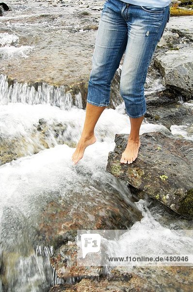 Niedrige Schnittansicht der Frau stehend auf Felsen in river