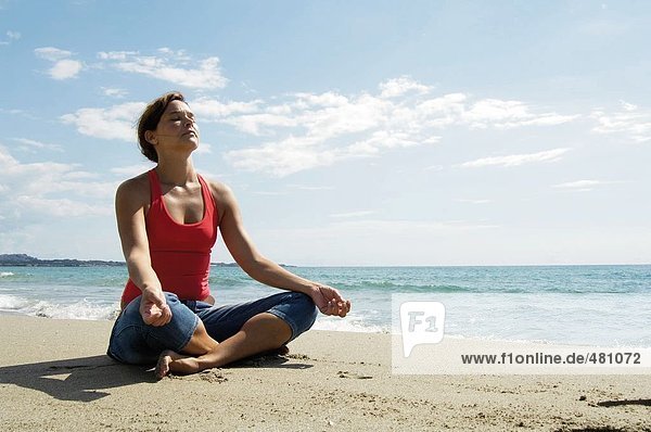Mid adult woman meditating on beach