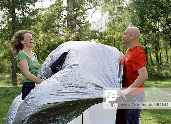 Zwei Personen ein Zelt einrichten.