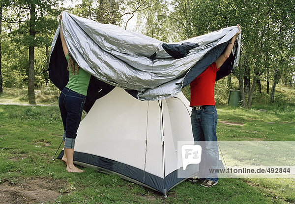 Zwei Personen ein Zelt einrichten.