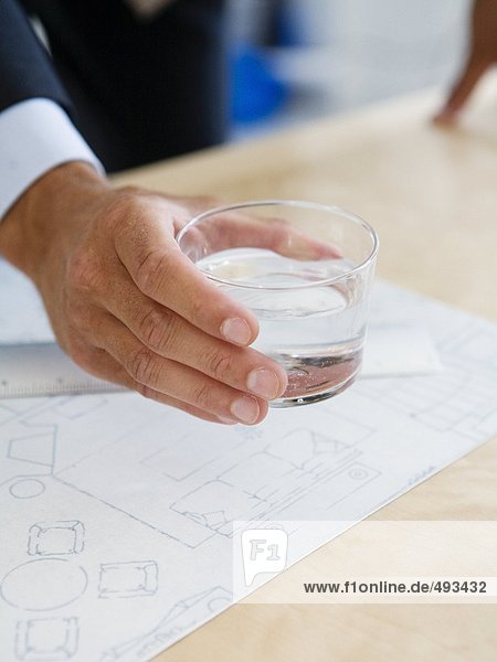 A glass of water in a hand in an office.