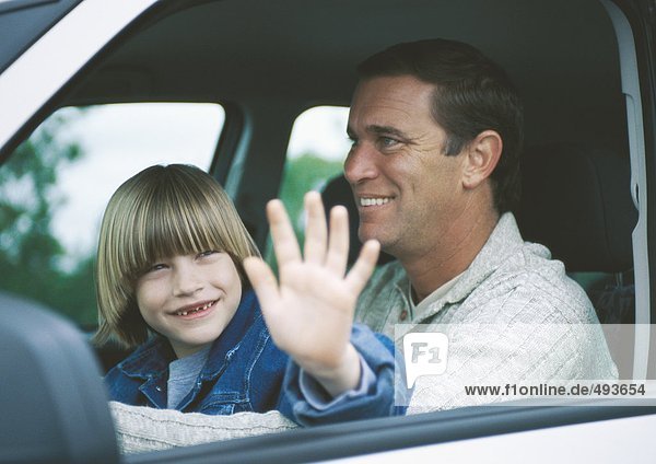 Boy sitting on father's lap in car