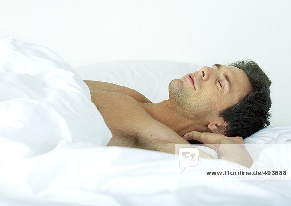 Man sleeping in bed with hands behind head