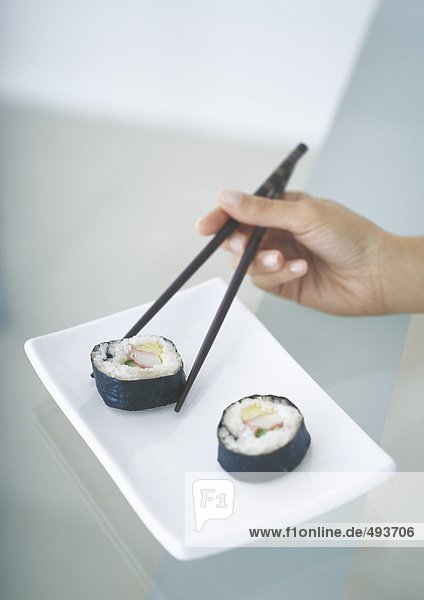 Sushi mit Essstäbchen aufheben